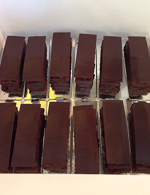 a dozen triple chocolate brownies in a catering box, viewed from above
