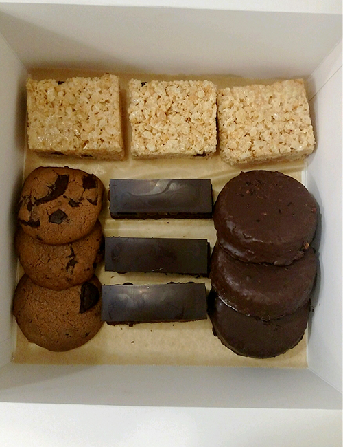 assorted box of treats includes rice krispy treats, chocolate chunk cookie, brownies, and coconut frangipane